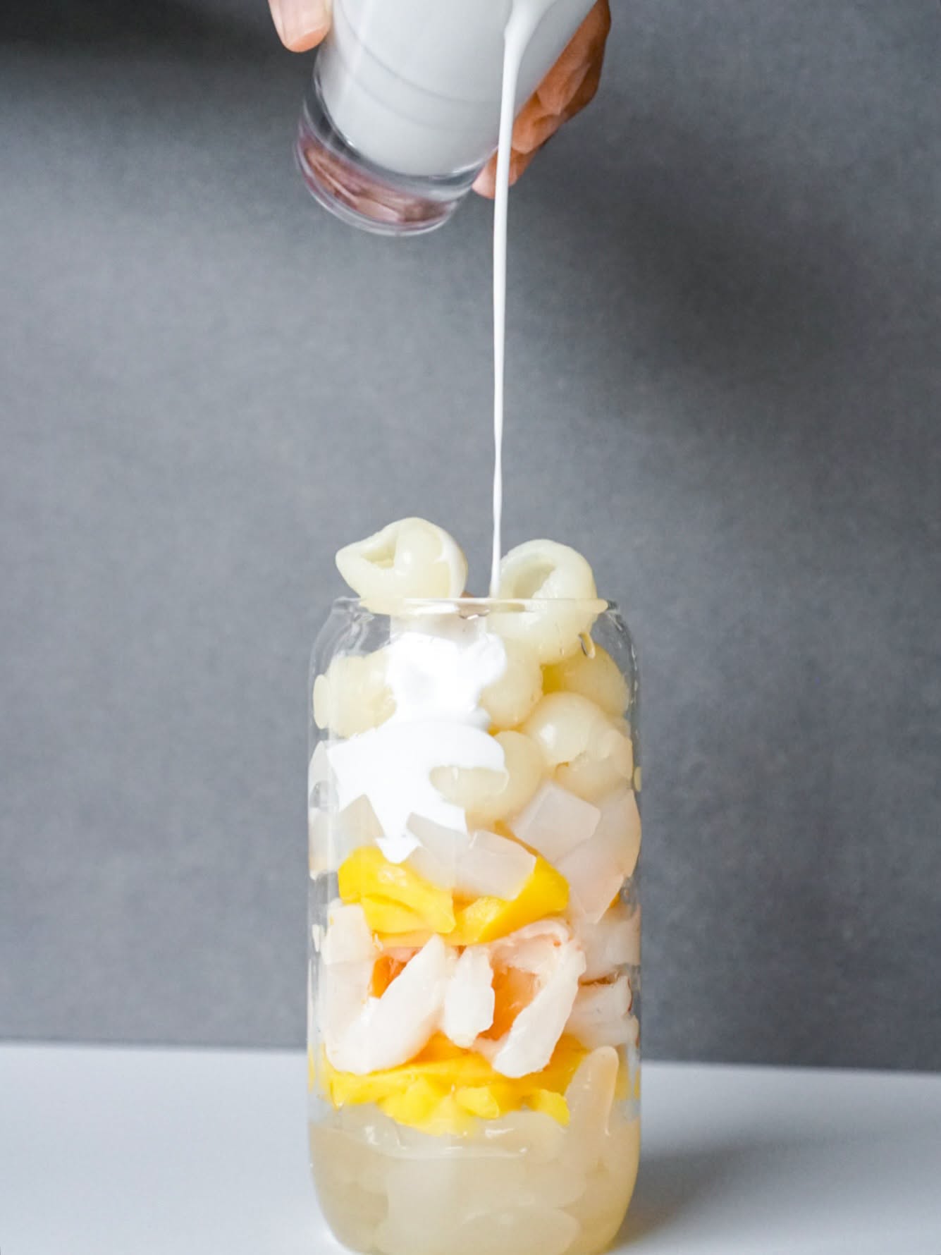 Lychee fruit tea being poured over jelly and fruit