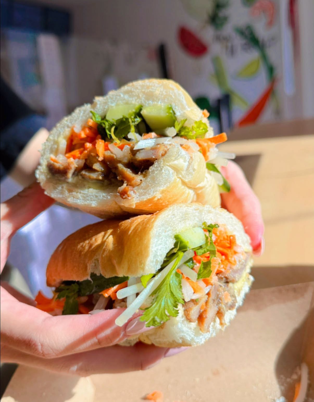 A halved V-Roll bánh mì held up in two hands