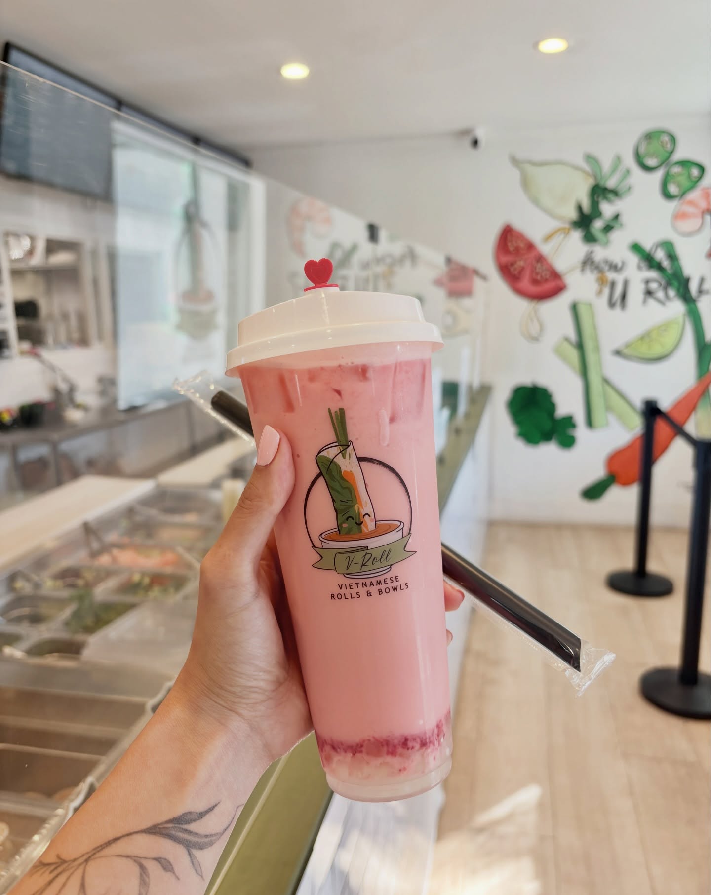 A strawberry boba in a V-Roll cup held up inside the restaurant