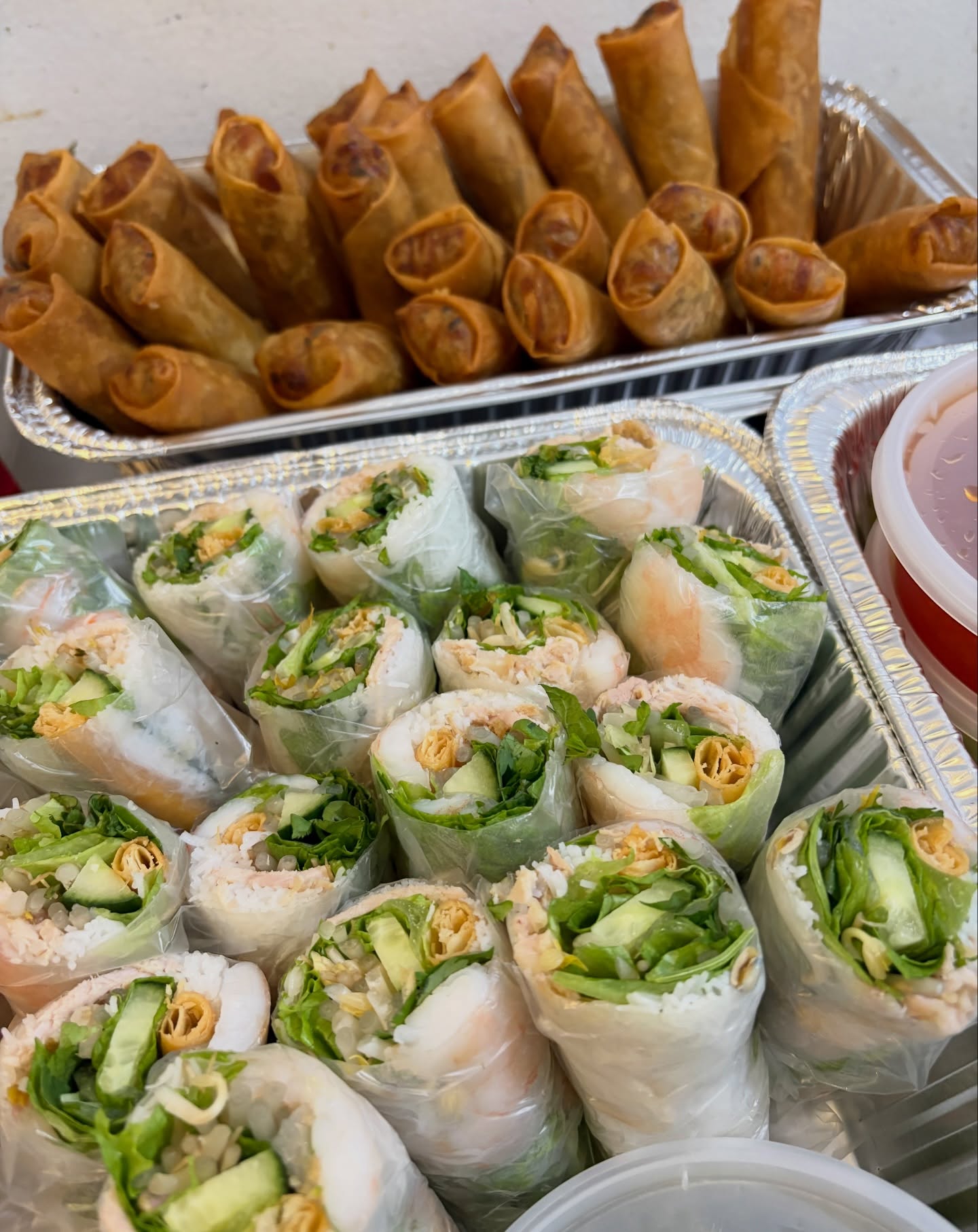 Catering trays of egg rolls and spring rolls packed for pickup