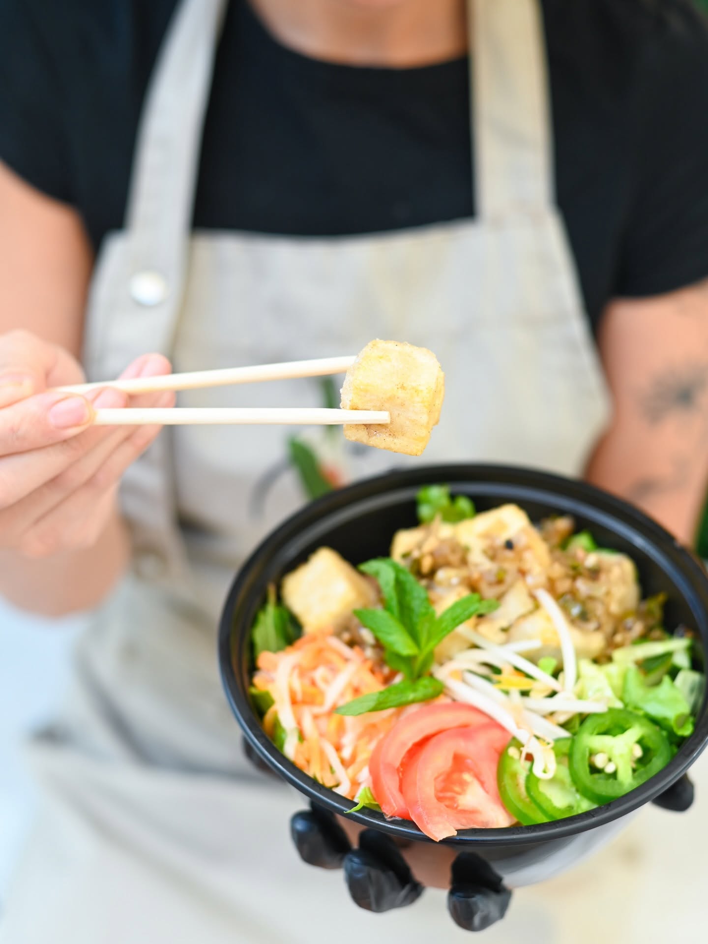 A V-Roll bowl of five-spice tofu, tomato and herbs lifted toward the camera