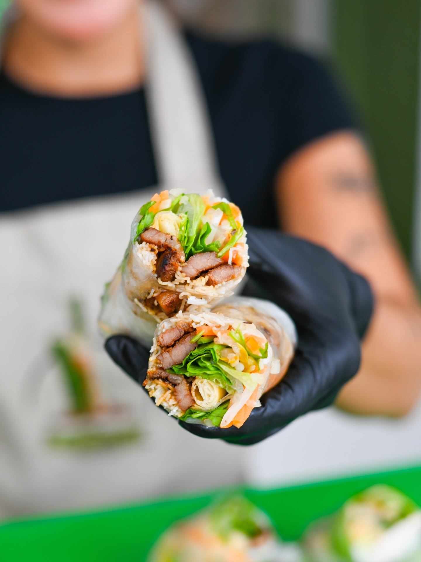A halved spring roll held out in a gloved hand