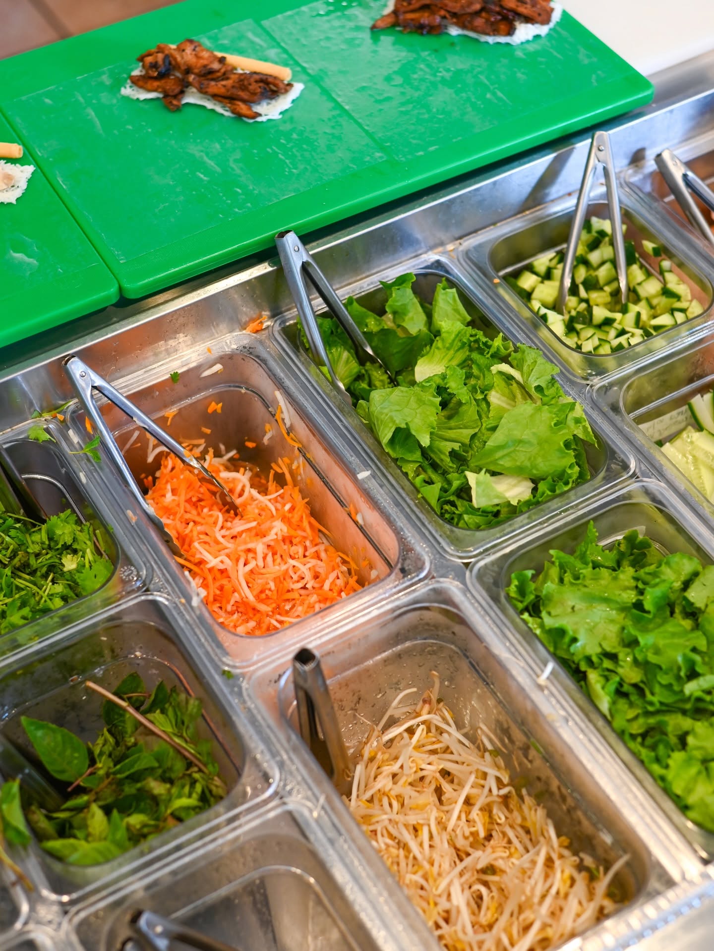 Steel inserts of fresh herbs and pickles on the prep line