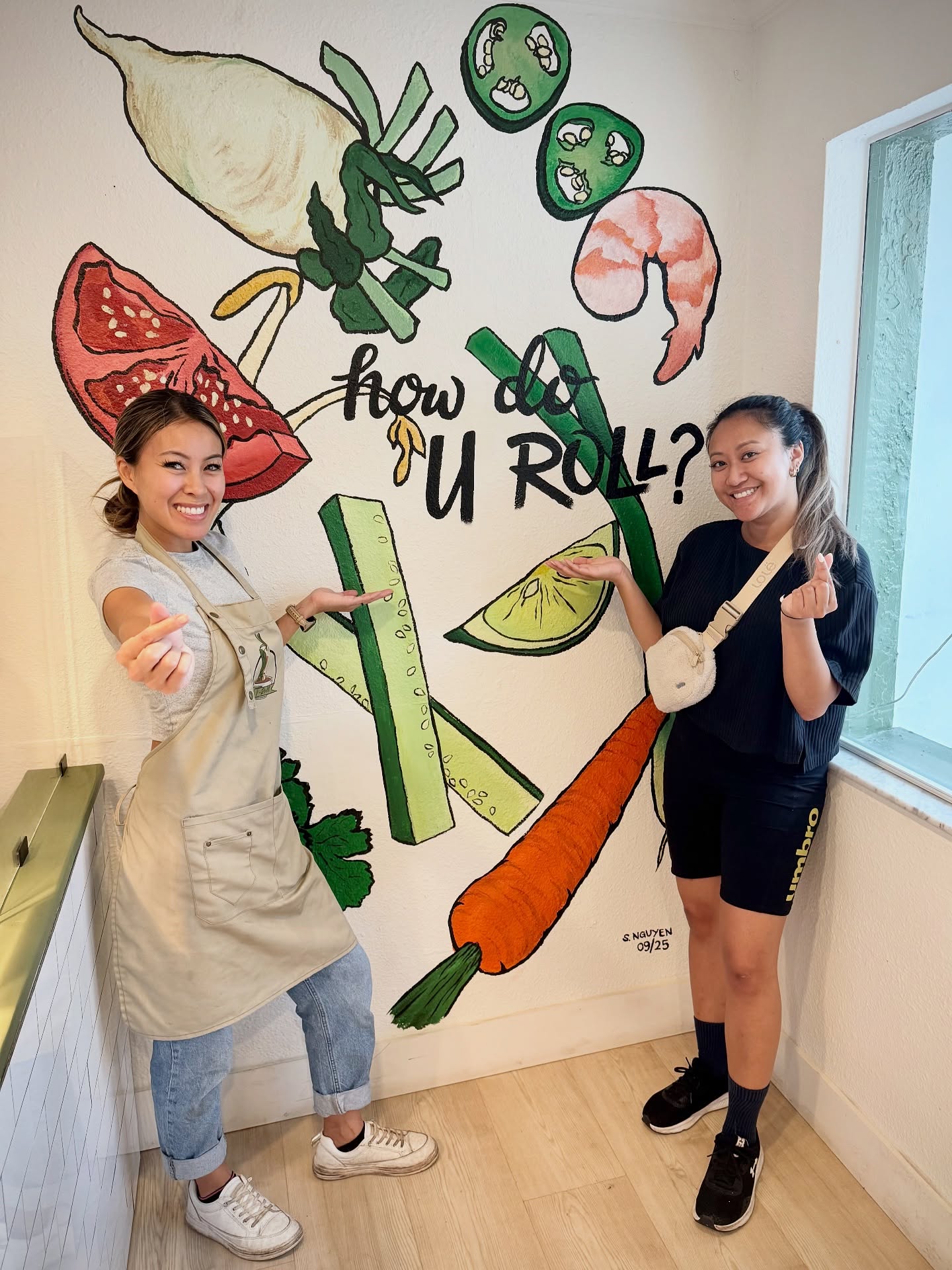 Two V-Roll team members posing at the hand-painted how do U roll? mural
