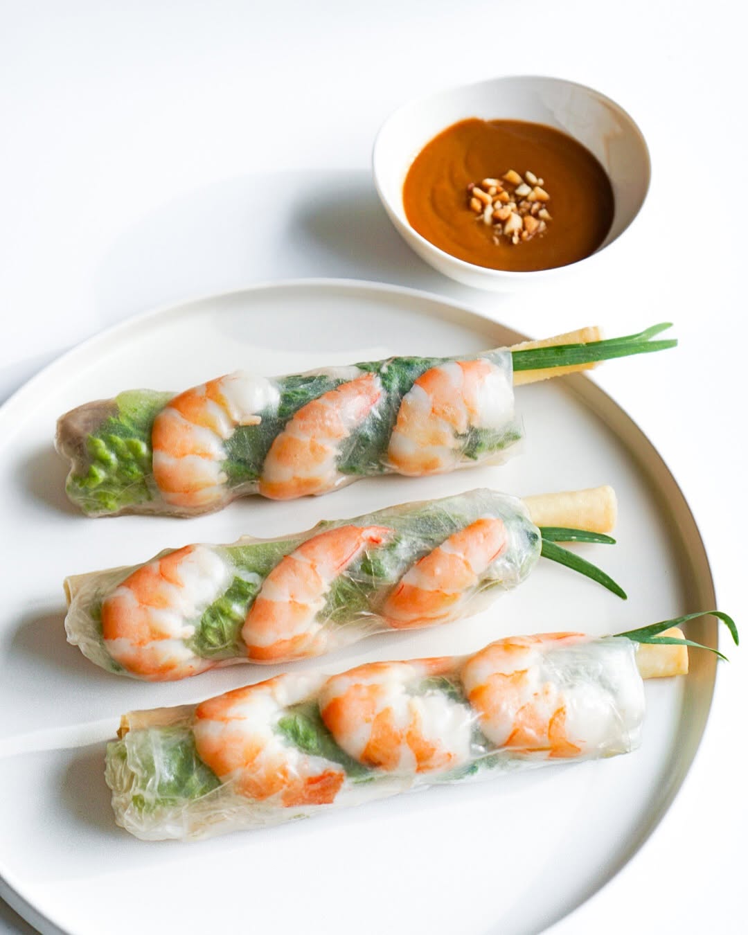House shrimp spring rolls (Gỏi Cuốn) on a white plate with a cup of V-Roll peanut sauce