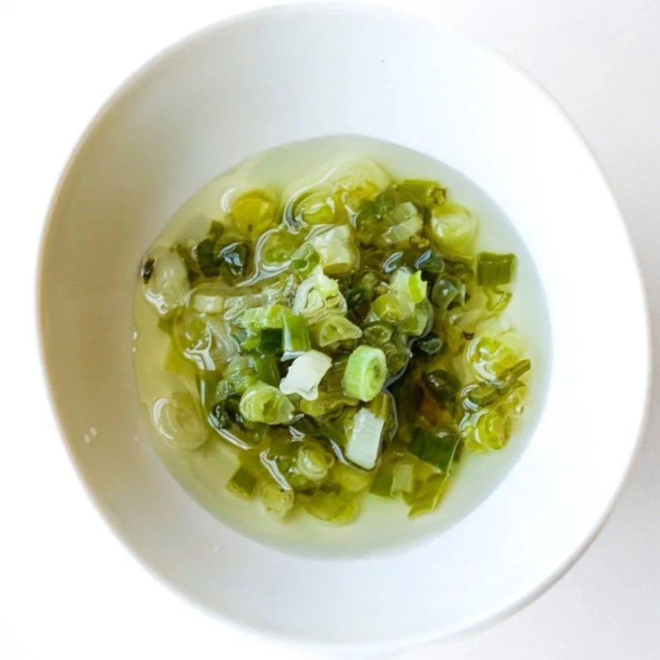 Green onion infused oil, from above in a white dish